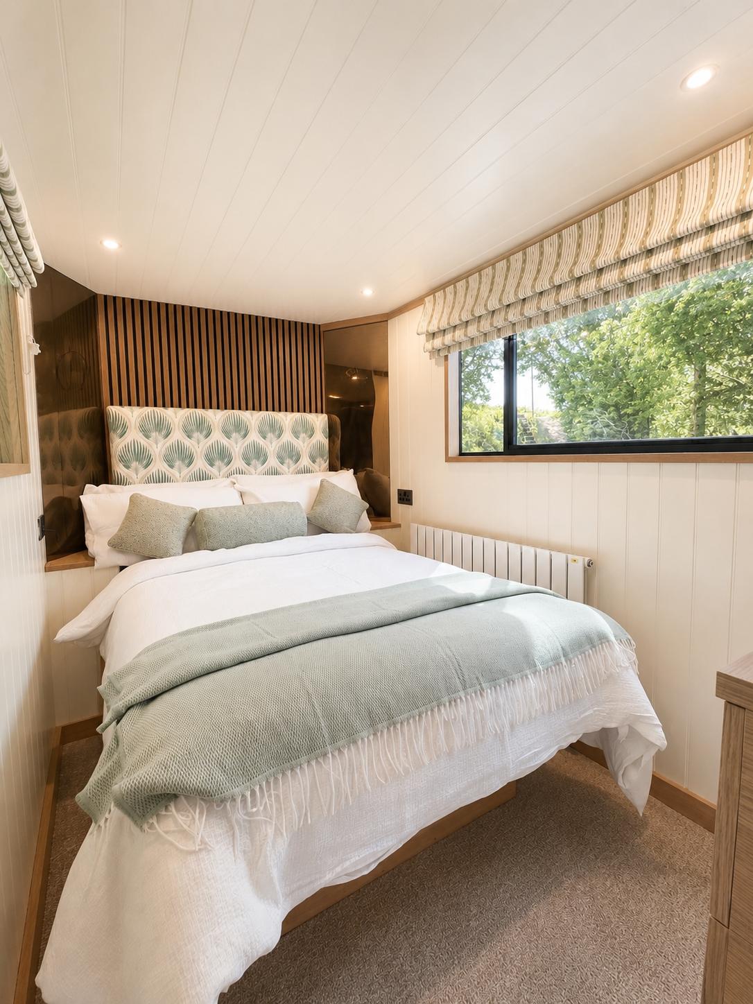 Theta bedroom with patterned green headboard, white bedding and natural oak joinery