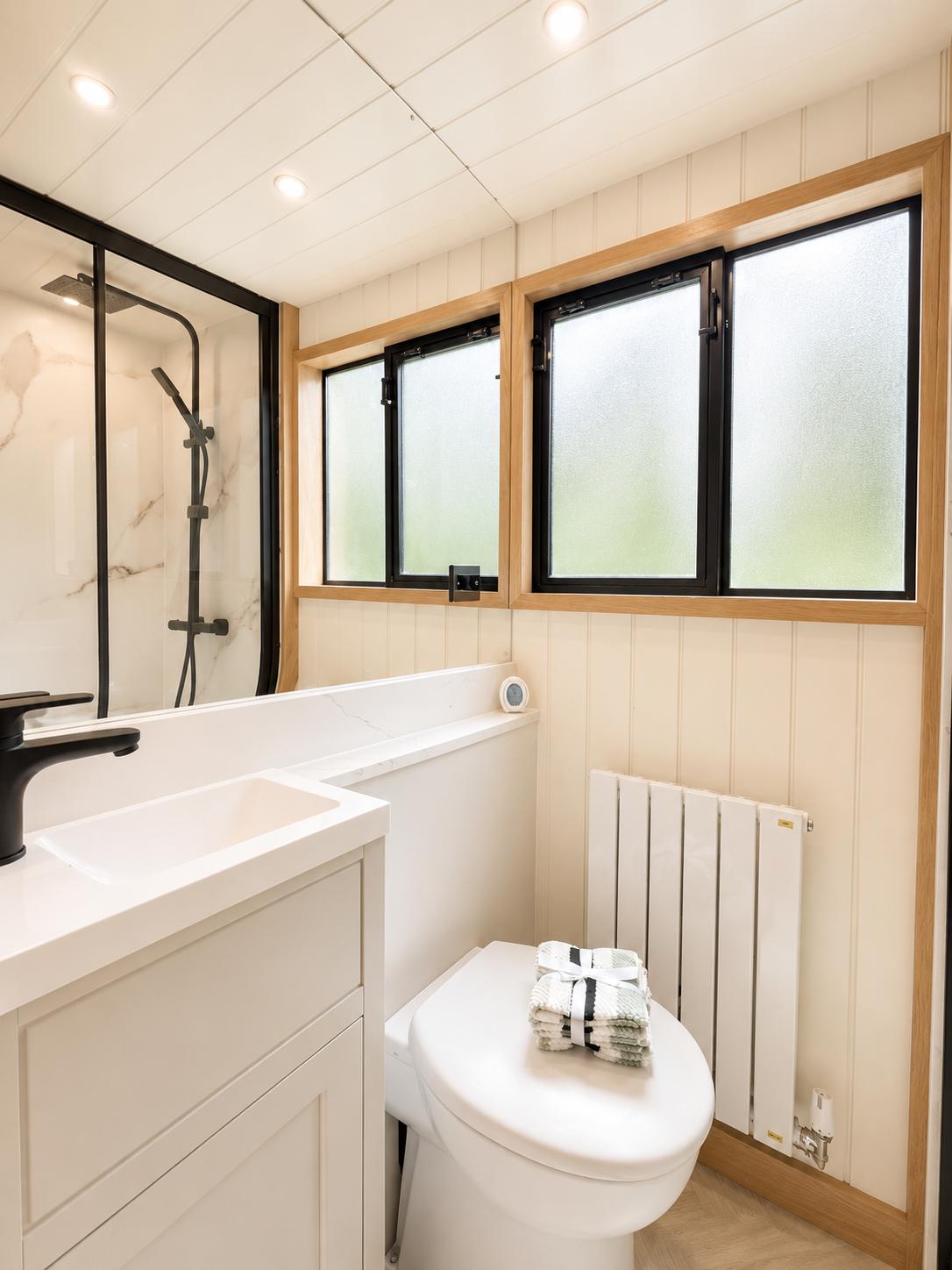 Theta shower room with marble effect surfaces, black fittings and white panelling